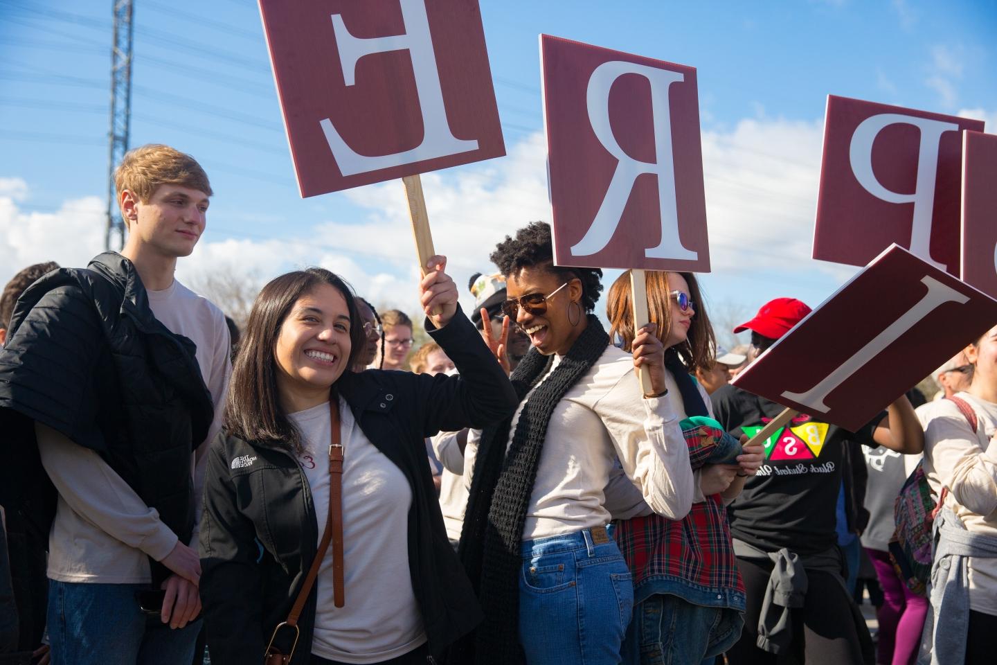 students hold signs that say "INSPIRE" at the Martin Luther King Jr. March
